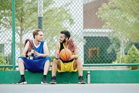 快乐的青年运动员在户外打篮球后刮胡子喝水和讨论游戏图片