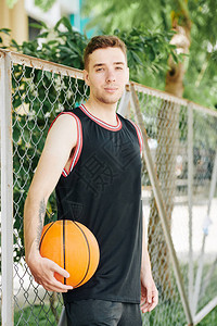 身穿黑色运动制服的英俊正帅青年男子在户外篮球场周围图片