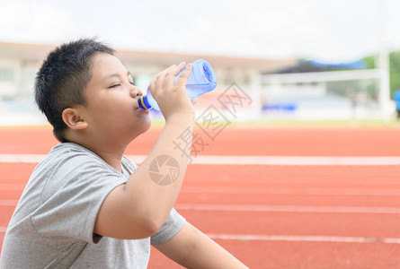肥阿相男孩在跑道旁用塑料瓶喝水图片