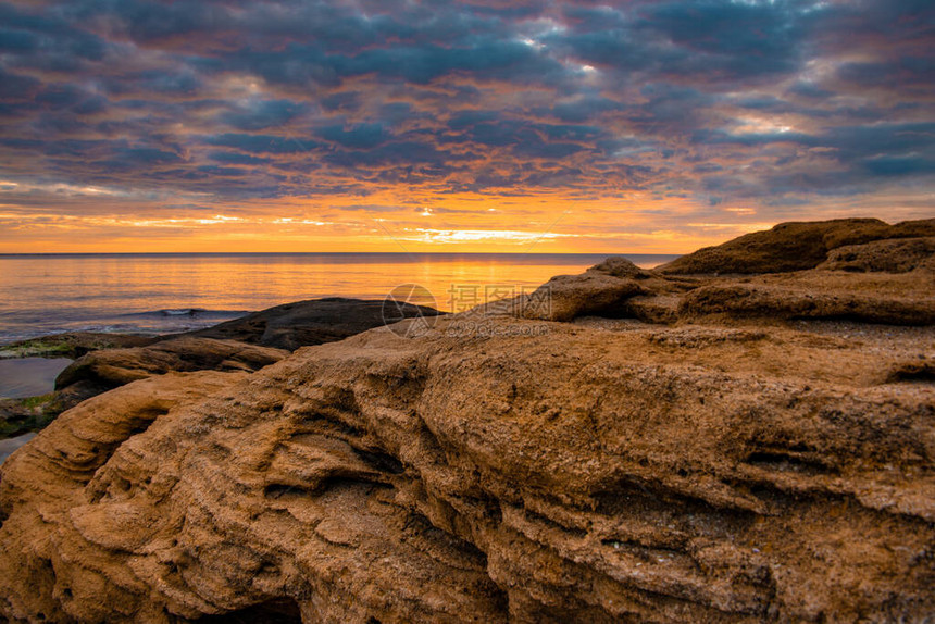 桑迪海滩岩石以橙色颜在太阳图片