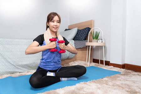 有吸引力和健康的年轻亚洲女在卧室的垫子上穿着舒适的衣服锻炼时在家锻炼图片