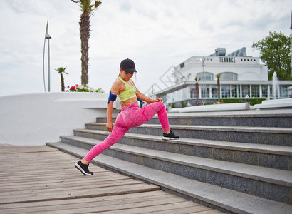 穿运动服的体操女子在楼梯室外做伸展腿锻炼图片