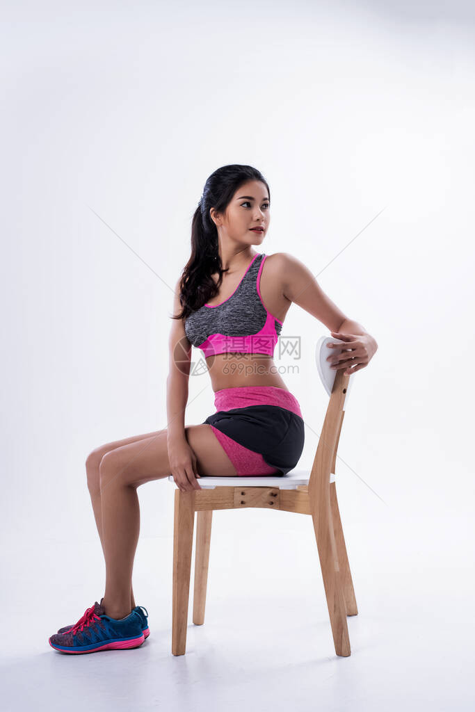 年轻漂亮的女士穿着运动服坐在木椅上伸手触摸靠背和扭动身图片
