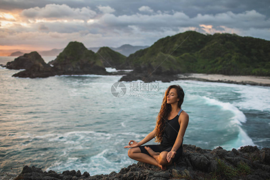 年轻女子在莲花练习瑜伽姿势在日落与美丽的海景和山景对自然的敏感自我分析和反省精神图片