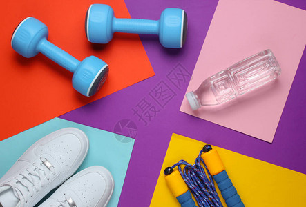 平躺式运动理念哑铃运动鞋跳绳瓶装水彩色背景上的运动器材复制图片