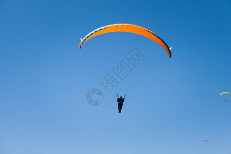 橙帆在蓝天飞翔的滑翔伞图片