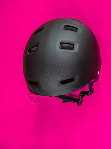 强烈的粉红色背景上的黑色头盔背景图片