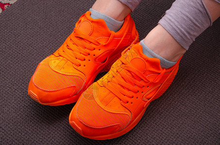 灰色Karimat高底灰色垫子上穿着橙色运动鞋的女腿图片