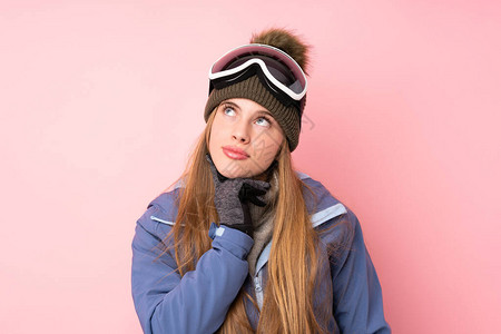 穿着滑雪眼镜的滑雪少女在孤立的粉红背景中图片