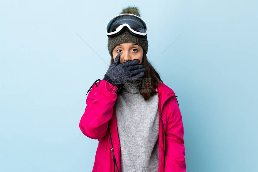 身戴滑雪眼镜的混血儿滑雪女郎在孤立的蓝色背景上图片