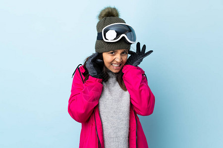 身戴滑雪眼镜的混血游玩女孩在孤立的蓝色背景下感图片