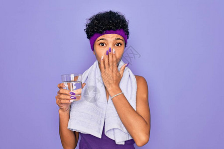 美丽的非洲裔美国运动女穿着毛巾喝水杯盖嘴做运动图片