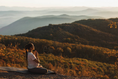 孕妇在日落时独自在山上户外祷告图片