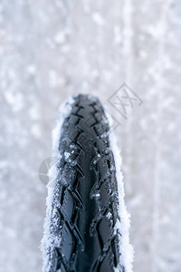 关闭在白色冰冷的道路上的自行车轮在极端冬季条件下骑自行车的概图片