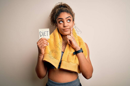 身穿毛巾的年轻美国女运动员拿着提醒带饮食信息严谨地面对问题非常困惑的想法图片