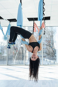 漂亮苗条的女人在健身房里用吊床练习空中倒立反重力瑜伽图片