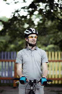 运动服和头盔中的赛车员站在公园的公路上图片