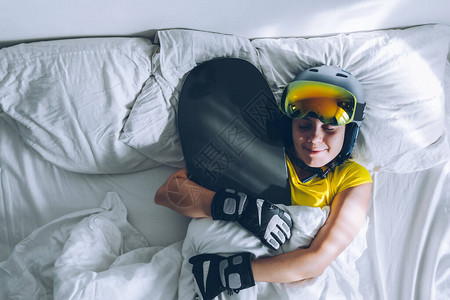 睡在床上与雪板一起滑雪的女人梦想着图片