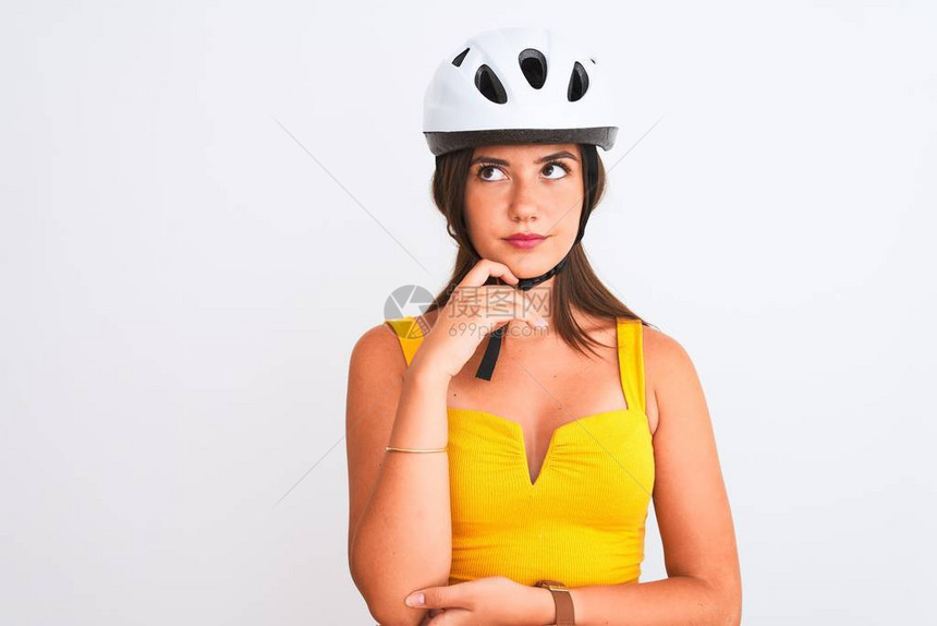 年轻漂亮的骑自行车的女孩戴着自行车头盔站在孤立的白色背景上图片