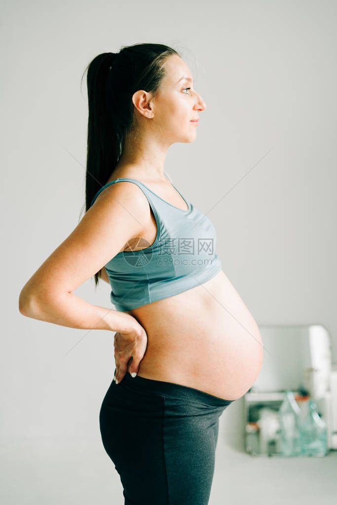 一名身穿运动服的怀孕少女站在瑜伽马特上图片