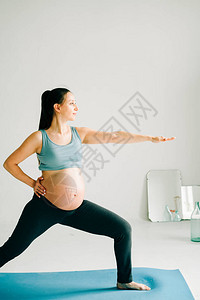 在运动服上做瑜伽的年轻怀孕少女图片