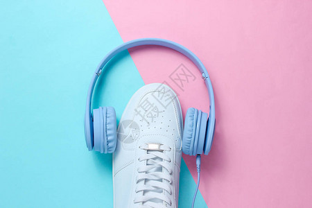 最小化音乐爱好者耳机穿蓝色粉面纸背景的白色运动鞋图片