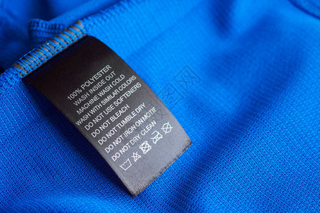 蓝色针织涤纶运动衫上的黑色洗衣护理洗涤图片