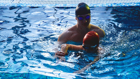 爸和教练小男孩游泳玩得开心在蓝泳池图片