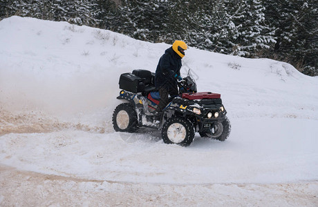 一名骑着ATV的摩托车手在雪地冬季森图片