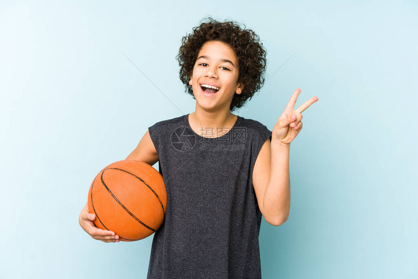 玩篮球的男孩在蓝背景上被孤立图片