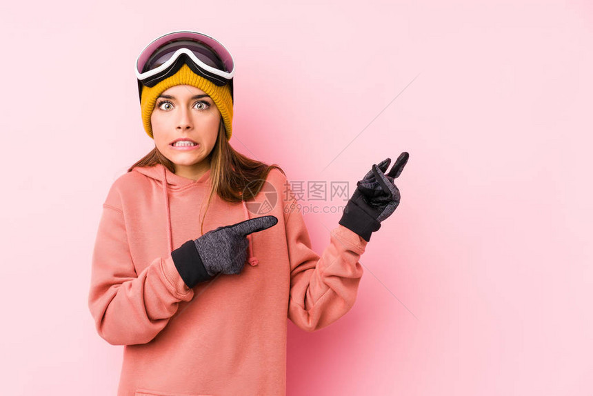 身着滑雪衣的年轻caucasian女子被孤立地震惊地用指数手指图片