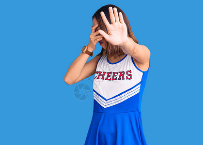 身着啦队员制服的年轻女孩用双手遮住眼睛背景图片