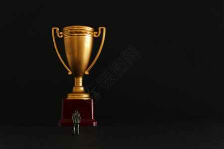 商业人的概念形象站在金奖杯的前面胜利成就和成功的图片