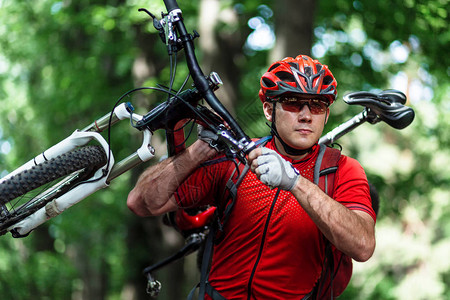 积极运动的男肩扛着山上自行车图片