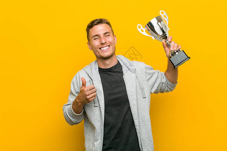 年轻caucasian男子拿着奖杯微图片