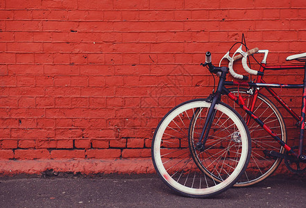 两辆旧自行车靠红砖墙停车图片