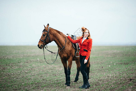 穿红色羊毛衣的红头发骑马女孩穿着黑色高靴子图片
