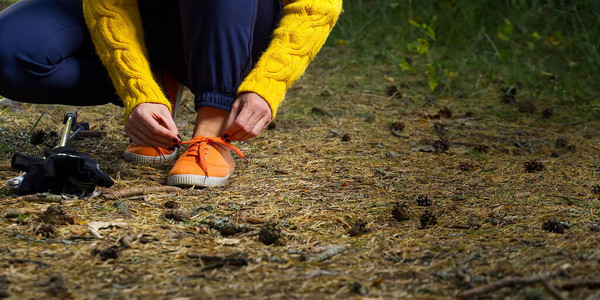 运动型远足妇女在秋季森林远足后休息时系在她的慢跑鞋上的鞋带图片
