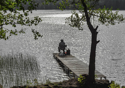 湖上的渔民在秋天的一天用钓鱼竿钓鱼图片