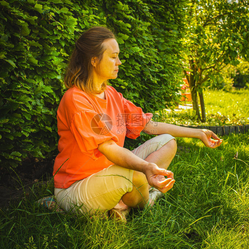 中年妇女坐在绿色花园背景的沉思图片