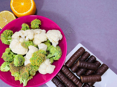 食物西兰花和巧克力的选择盘子里有蔬菜水果巧克力是一种垃圾食品选择健康的图片
