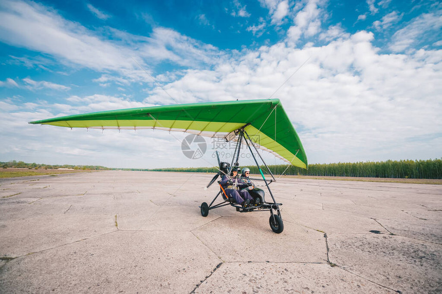 摩托悬吊滑翔机从草场跑道起飞在蓝天和图片