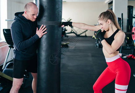 男教练训年轻女子在健身房打拳图片