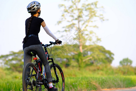 运动女运动员骑自行车在路边的路上以自图片