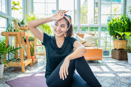 微笑快乐美丽的亚洲年轻健身运动女在家休息疲惫和伸展运动图片