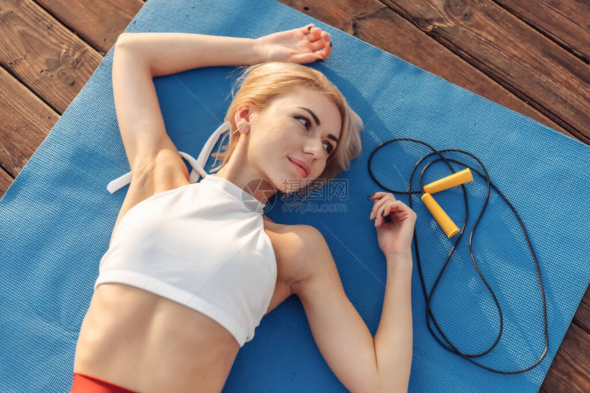 运动服中的美容女子躺在室外的垫子上健康图片