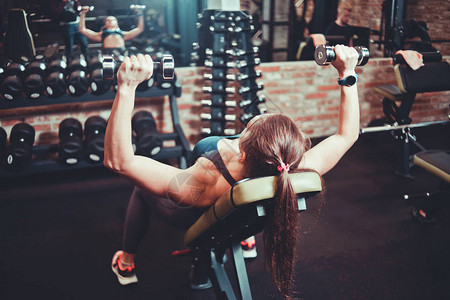 年轻女子在健身房用哑铃做运动图片