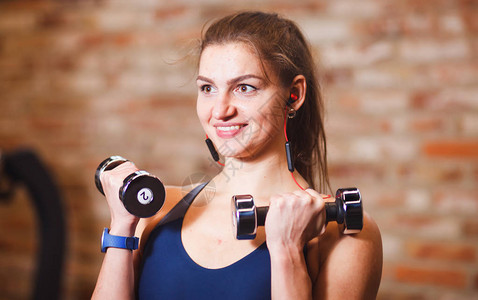 运动女运动员在健身房用哑铃做操练习图片