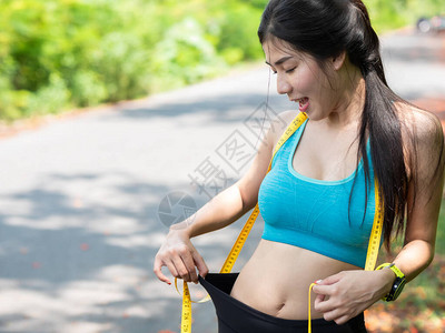美丽的亚洲年轻女子身体在运动服和胶带测量中瘦弱图片