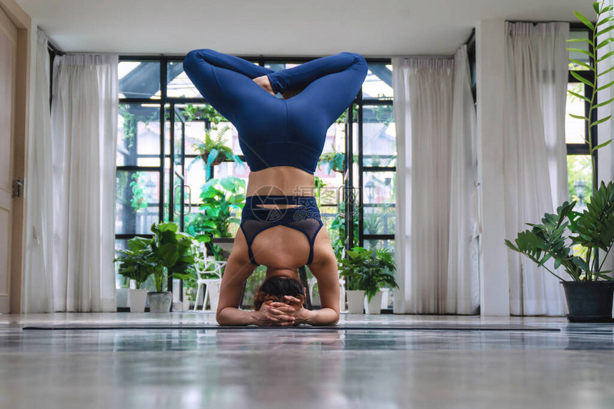 活动年轻女穿着蓝色运动服在垫子上做姿势排毒瑜伽序列放松女孩在家练习高级瑜伽保持身体健康生活方式锻炼以获得良图片